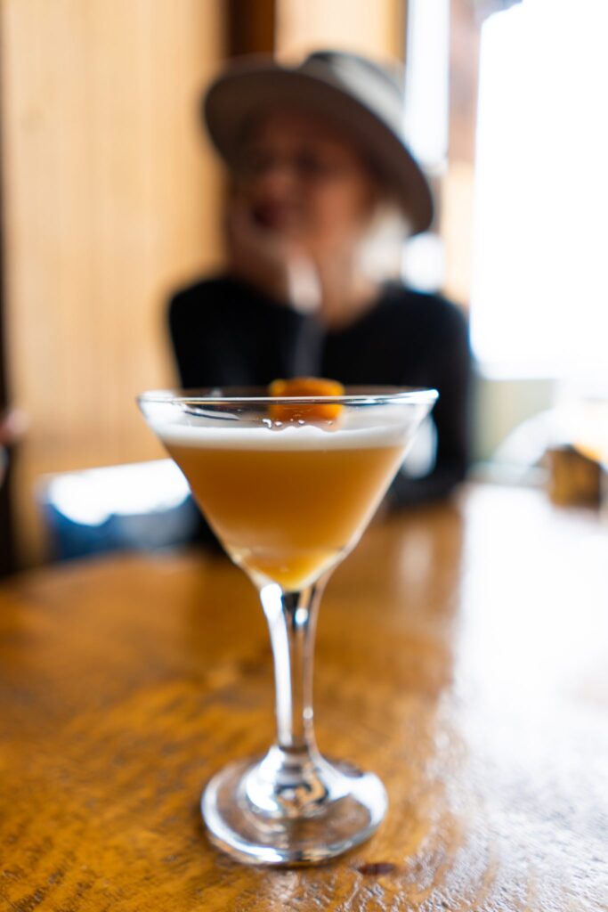 A golden Asulkan Sour cocktail in a coupe glass at Cliffhouse Bistro, Banff.