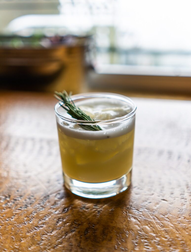 Coconut Abbot Pass Sour cocktail with rosemary garnish at Cliffhouse Bistro, Banff.