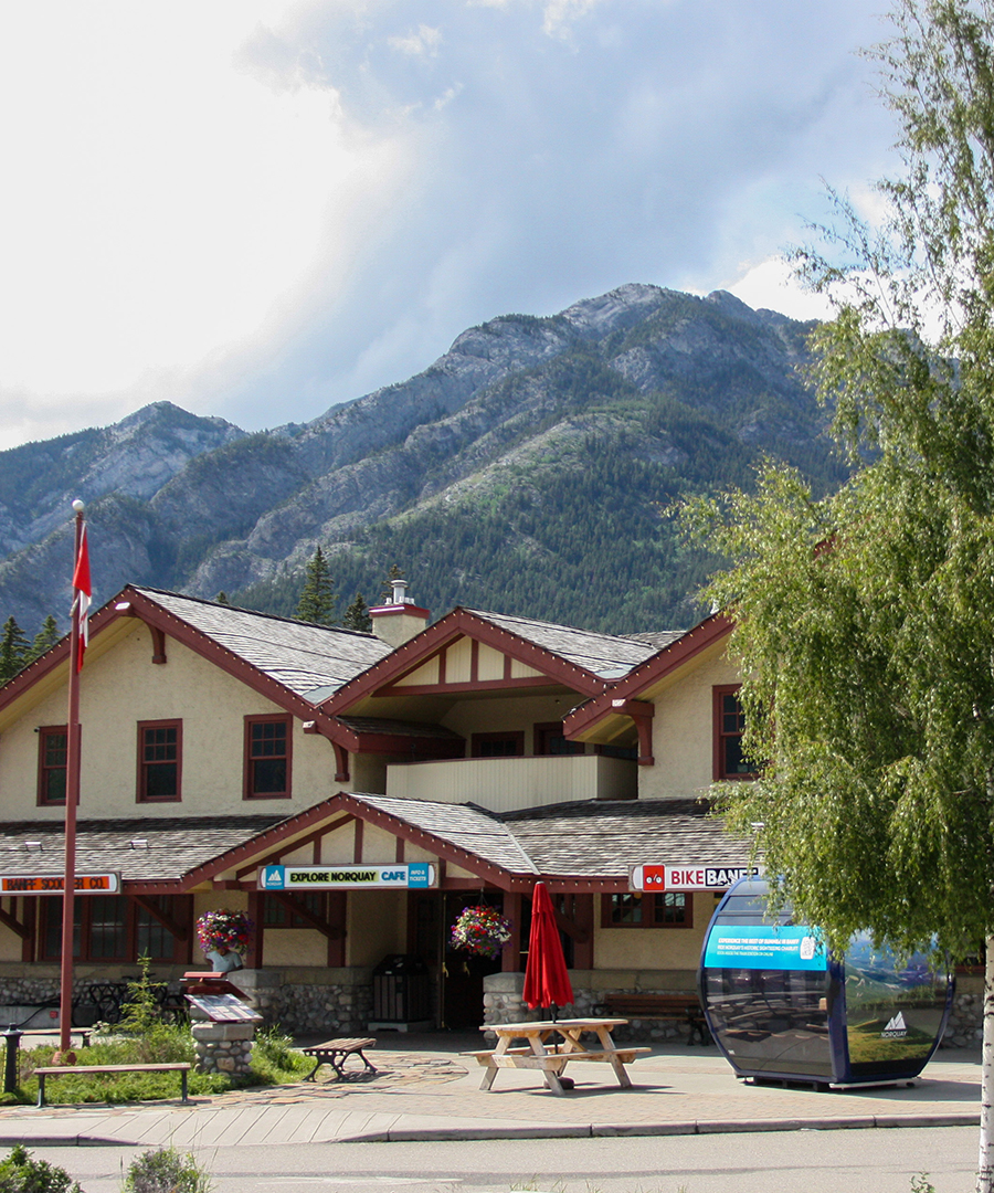 Banff chalet with Canadian flag beneath a stunning Rocky Mountain peak, Alberta.